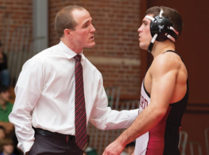 a wrestling coach standing with a male wrestler showing the role of wrestling coaches in Athlete Development 