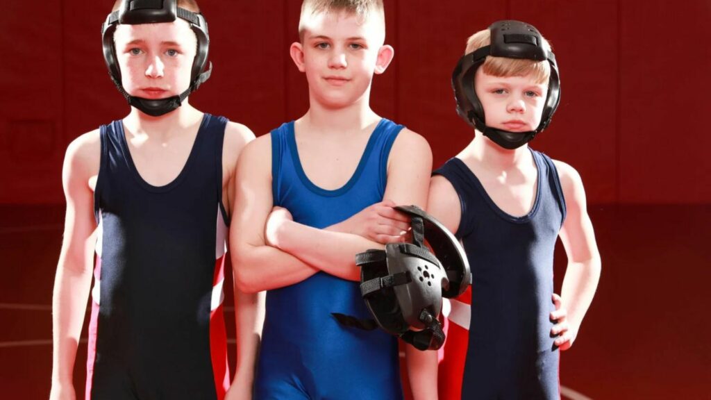 3 boys standing wearing wrestling kit showing How to Start a Youth Wrestling Club